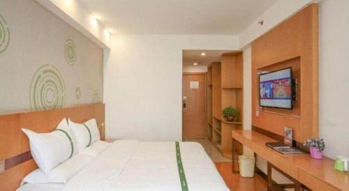 a hotel room with a bed and a flat screen tv at GreenTree Inn Jinzhong PinGYAo City South Railway Station Express Hotel in Pingyao