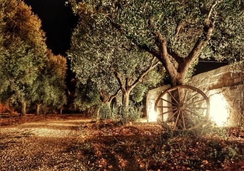 an old wagon wheel sitting next to a stone wall and trees at Oltre gli Ulivi in Ostuni