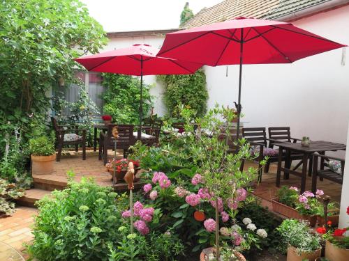 a patio with two red umbrellas and tables and flowers at Stieglerhof KG in Illmitz