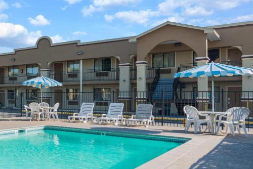 a pool with chairs and umbrellas next to a building at Days Inn by Wyndham San Marcos in San Marcos