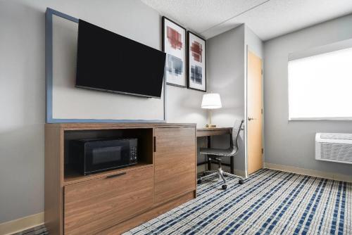 a hotel room with a flat screen tv and a desk at AmericInn by Wyndham Wausau in Weston