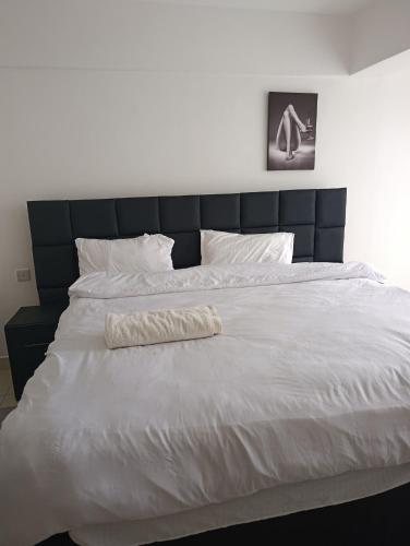 a large white bed with a black headboard and white pillows at Starla one bedroom duplex in Kinoo