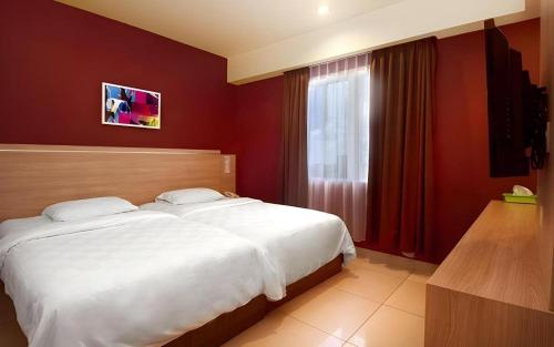 a bedroom with a large white bed and a window at Borneo Hotel in Pontianak