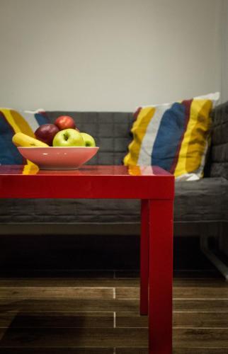 a bowl of apples on a red table with a couch at B&B Cool Centre Zagreb in Zagreb