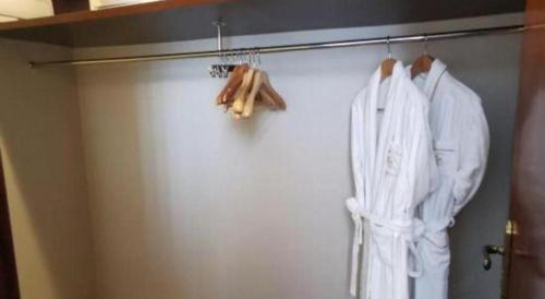 a closet with white clothes hanging on a wall at Jinjiang Metropolo Shanghai Minhang in Shanghai