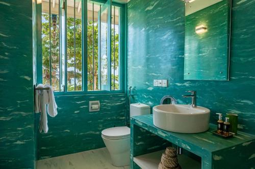 a blue bathroom with a sink and a toilet at Monara - Tangalle in Tangalle
