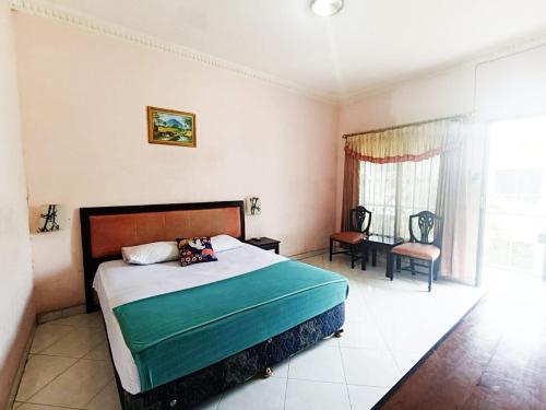 a bedroom with a bed and a chair and a window at YUTAKA INN Global Juanda Sidoarjo in Kalangan