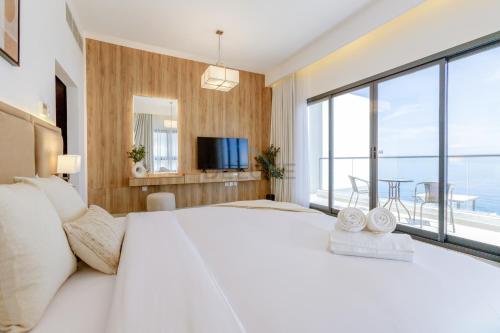 a bedroom with a large white bed and a large window at Elegant 4BR Villa with Arabian Gulf, Mountain and Community Views, Assistant Room and Heated Pool, Al Dana Island, Fujairah by Deluxe Holiday Homes in Fujairah