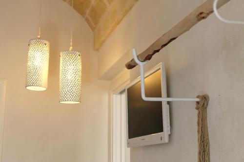 two chandeliers and a tv on a wall at Oltre gli Ulivi in Ostuni