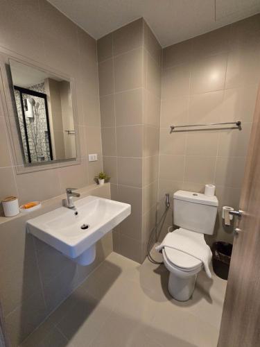 a bathroom with a white toilet and a sink at La Habana Huahin by J2A in Hua Hin