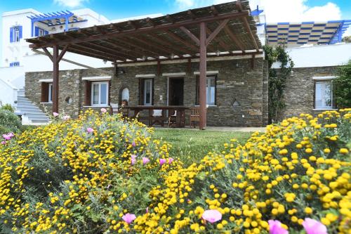 una casa de piedra con pérgola de madera y flores en Tinos Sky View Villa en Arnados