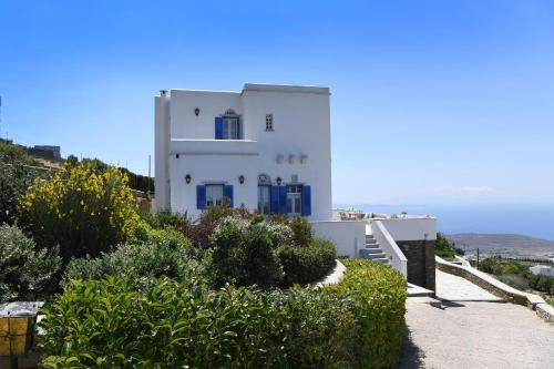 a white building with blue doors on a hill at Tinos Sky View Villa in Arnados