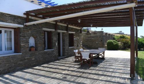 a patio with a table and chairs under a wooden pergola at Tinos Sky View Villa in Arnados