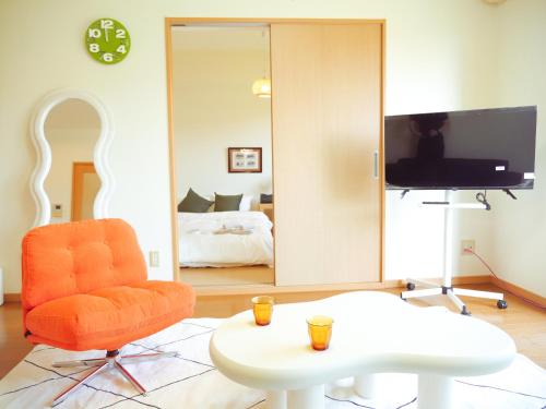 a living room with an orange chair and a tv at 9stay 出雲フォルクローロ in Taisha