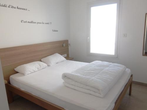 1 cama con sábanas blancas y almohadas en una habitación en Résidence Belle Plage, en La Tranche-sur-Mer