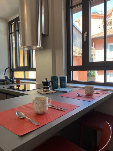 a kitchen counter with red napkins and two cups and spoons at Orta Lake Apartments II in Omegna