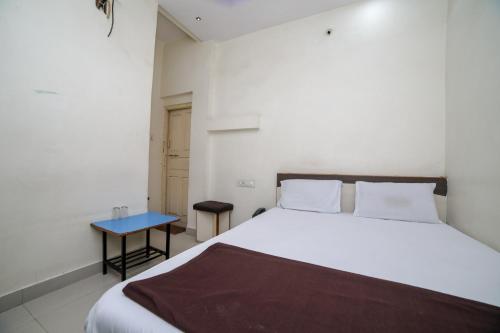 a bedroom with a white bed and a blue table at SPOT ON Shraddha Hotel in Nagpur