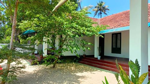 a house with a tree in front of it at Coconut Bay Marari in Mararikulam