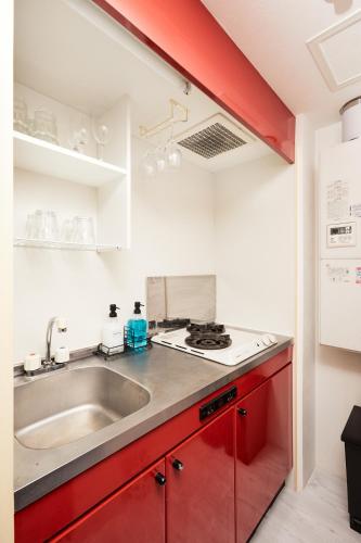 a kitchen with red cabinets and a sink at Shirogane Apartment in Tokyo