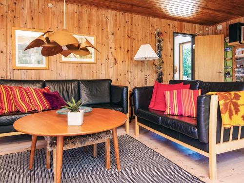 a living room with black leather couches and a table at 6 person holiday home in Rømø in Bolilmark