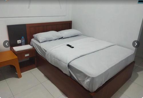 una cama con un celular sentado encima de ella en SG Hotel Pangandaran, en Pangandaran