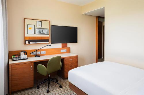 a hotel room with a bed and a desk with a television at Hilton Garden Inn Frankfurt Airport in Frankfurt/Main