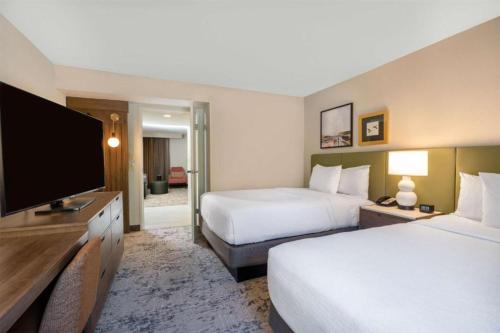a hotel room with two beds and a flat screen tv at Embassy Suites by Hilton Memphis East Germantown Area in Memphis