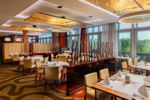 a restaurant with tables and chairs and large windows at Hilton Frankfurt Airport in Frankfurt