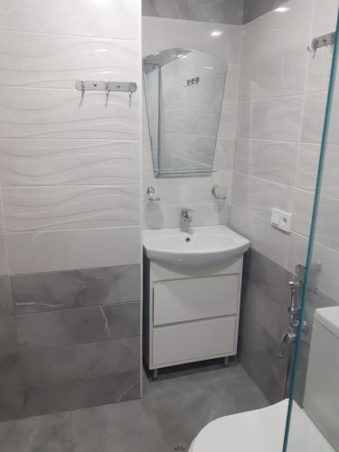 une salle de bain blanche avec un lavabo et un miroir dans l'établissement Дом в центре города, à Erevan