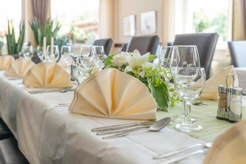 a table with a white table cloth and a vase of flowers at Ringhotel Alfsee Piazza in Rieste