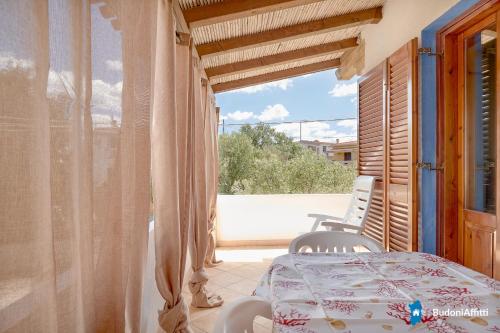 a room with a table and chairs on a balcony at Appartamenti 950 m dalla spiaggia by BudoniAffitti in Tanaunella