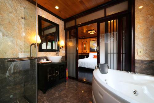 Un baño con bañera, lavabo y cama. en Victory Boutique Cruise, en Ha Long
