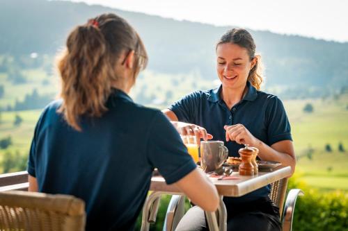 two women sitting at a table eating food at Domaine du Mont-Saint-Jean in Les Rousses