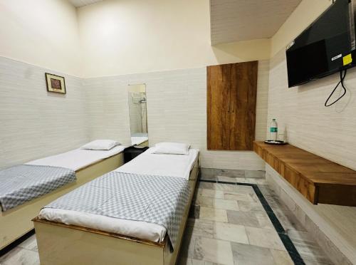 a room with two beds and a flat screen tv at House of Kashi Homestay- Studio and Budget Rooms in Kashi