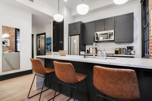 a kitchen with black cabinets and brown bar stools at Roami at The Lola Convention Center 1BR #13 in New Orleans