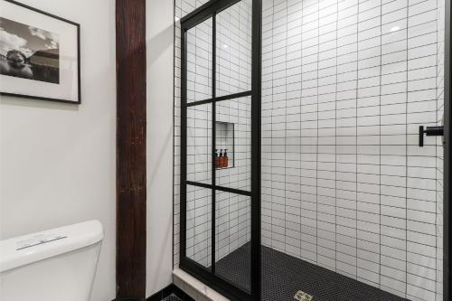 a shower with a glass door next to a toilet at Roami at The Lola Convention Center 1BR #13 in New Orleans