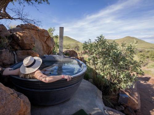 a woman is laying in a bath tub at Nauams Namibia - Farmyard Chalets, Mountain Cabins and Campsite in Namibgrens