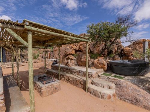 a wooden pavilion with steps and a fire place at Nauams Namibia - Farmyard Chalets, Mountain Cabins and Campsite in Namibgrens