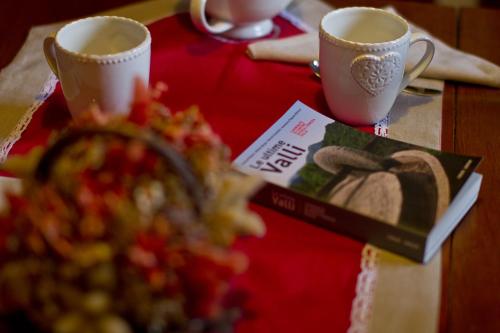 a table with two cups of coffee and a book at Casa Cebajova Poesia in Tribil di Sopra