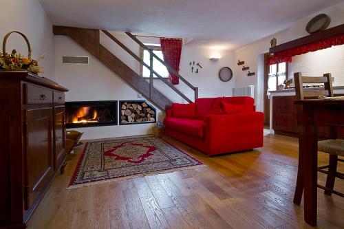 a living room with a red chair and a fireplace at Casa Cebajova Poesia in Tribil di Sopra