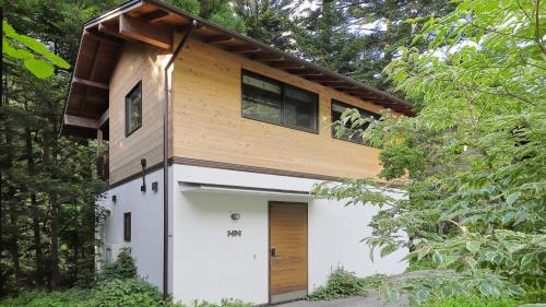 a house in the woods with a wooden roof at Onsen Glamping ShimaBlue in Nakanojo