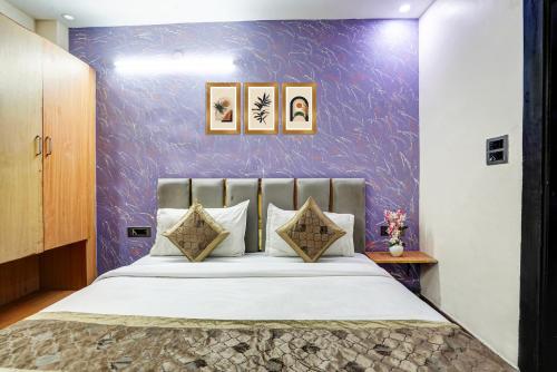 a bedroom with a bed with a purple wall at Hotel Twamev Couple Friendly Laxmi Nagar in New Delhi