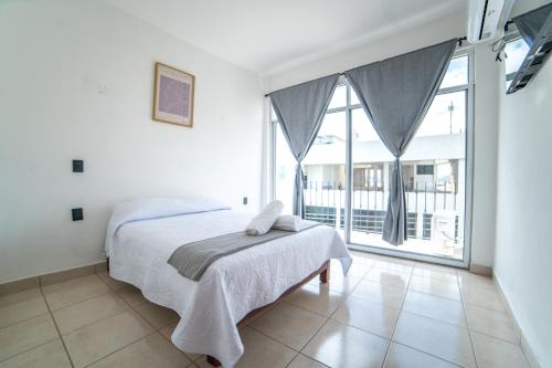 a bedroom with a bed and a large window at Hotel Catedral Jojutla in Jojutla