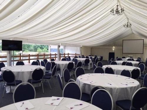 a large tent with tables and chairs and a screen at Crowne Plaza London - Kingston by IHG in Kingston upon Thames