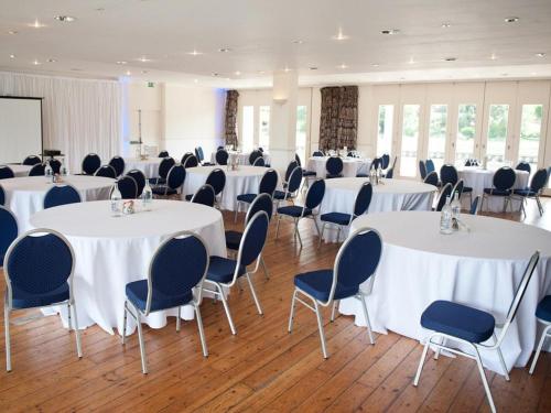 a room with white tables and chairs and a room with windows at Crowne Plaza London - Kingston by IHG in Kingston upon Thames