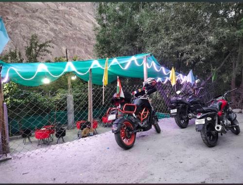 two motorcycles parked next to a fence and a tent at Apricot Cafe and Restaurant Shapa in Turtuk