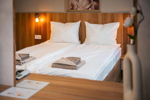 a bedroom with a bed with white sheets and pillows at TRINAVIS Boutique Apartments, OWN PRIVATE PARKING, City Center, Entire Apartment in Veliko Tŭrnovo