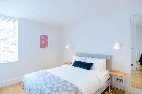 - une chambre avec un lit blanc et un oreiller bleu dans l'établissement Native Fulham, à Londres