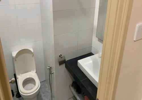 a small bathroom with a toilet and a sink at Cozy Hotel Primera Suite Cyberjaya in Cyberjaya