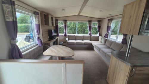 a living room with a couch and a tv in a caravan at Hot tub retreat, at Tattersall Lakes caravan in Tattershall